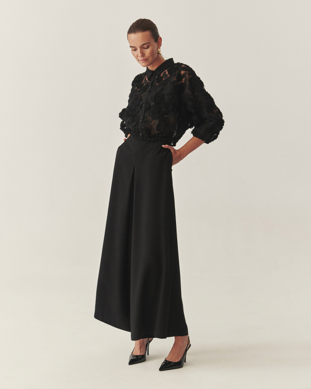 o femeie îmbrăcată într-o cămașă ornamentată și pantaloni lungi cu picioare largi