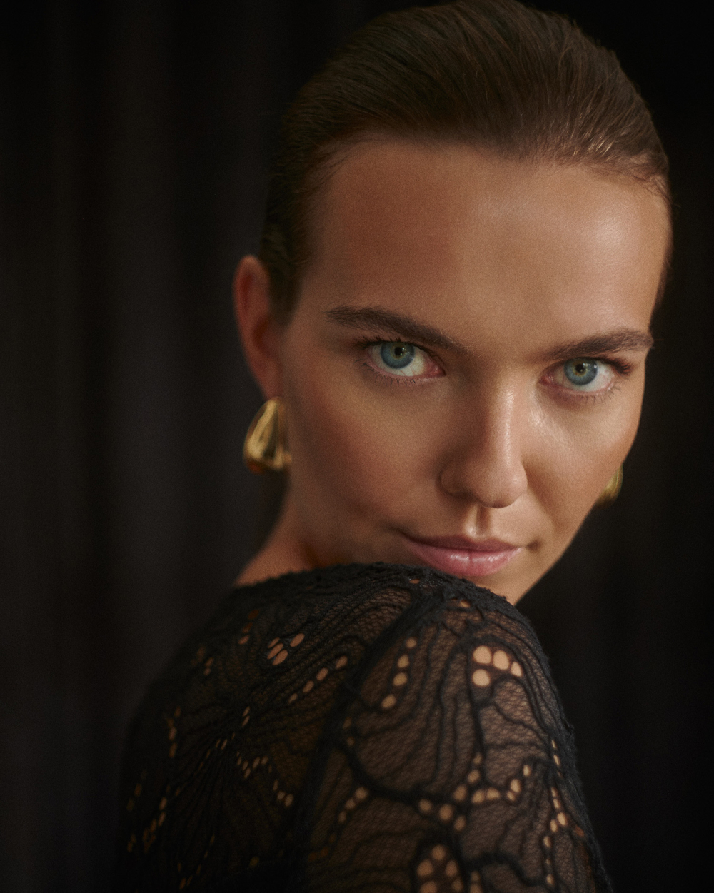 prim-plan al feței unei femei îmbrăcată într-o bluză din dantelă și cercei din aur