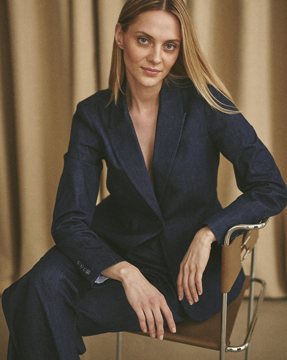 Modelka sedící na židli oblečená do módního džínového obleku