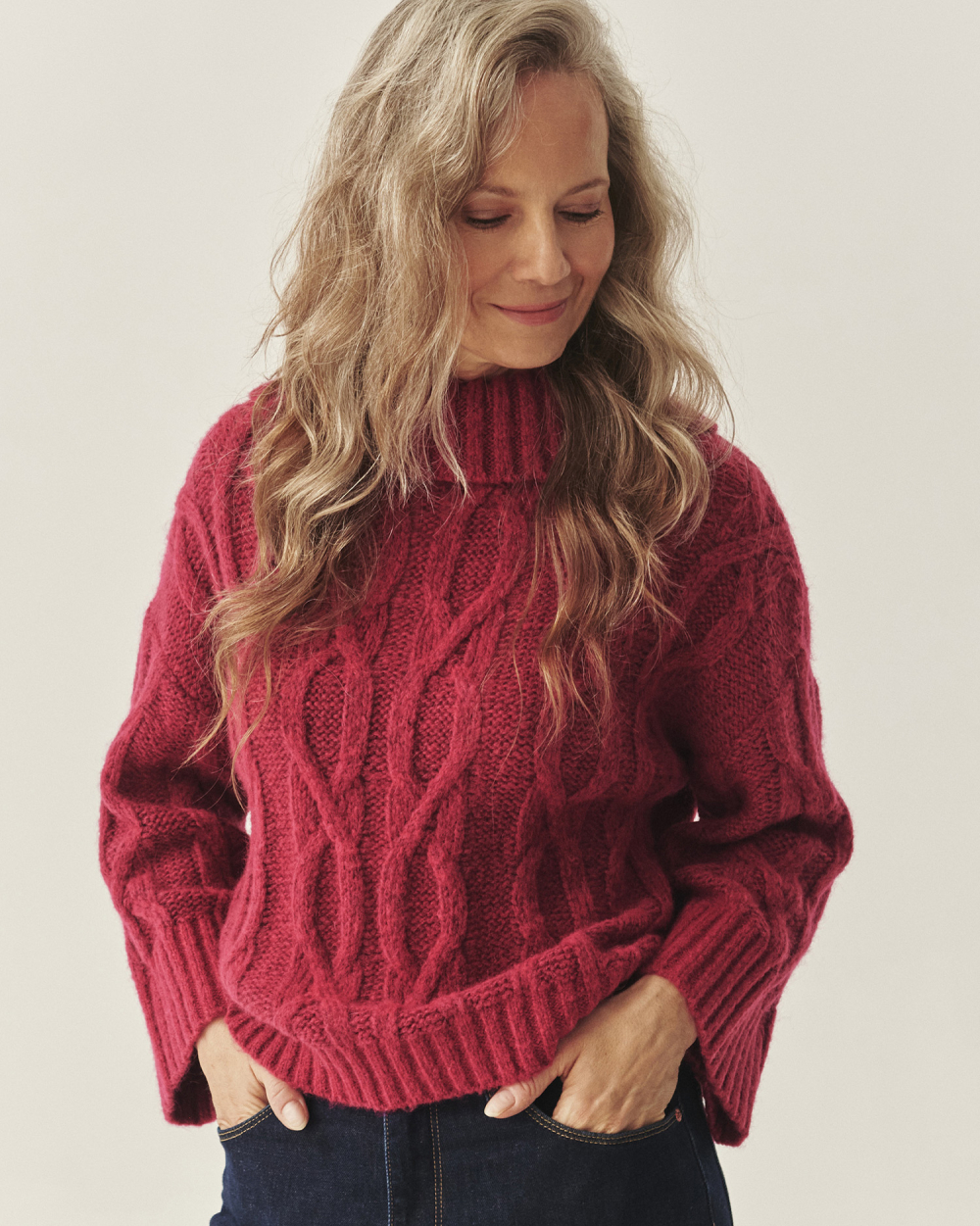 femeie zâmbitoare într-un pulover, privind în jos 