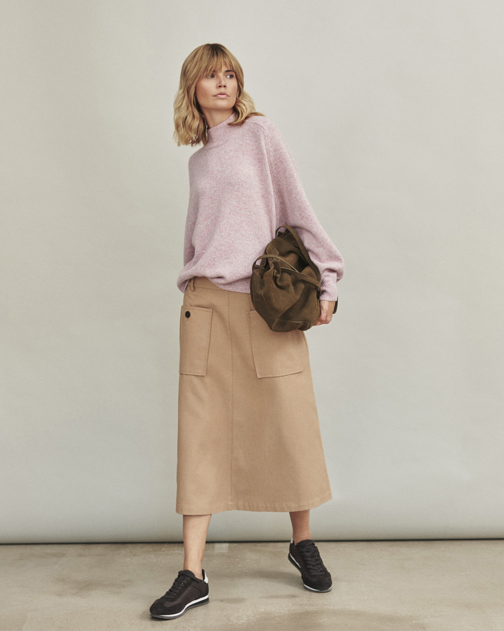 žena v béžové sukni a růžovém svetru