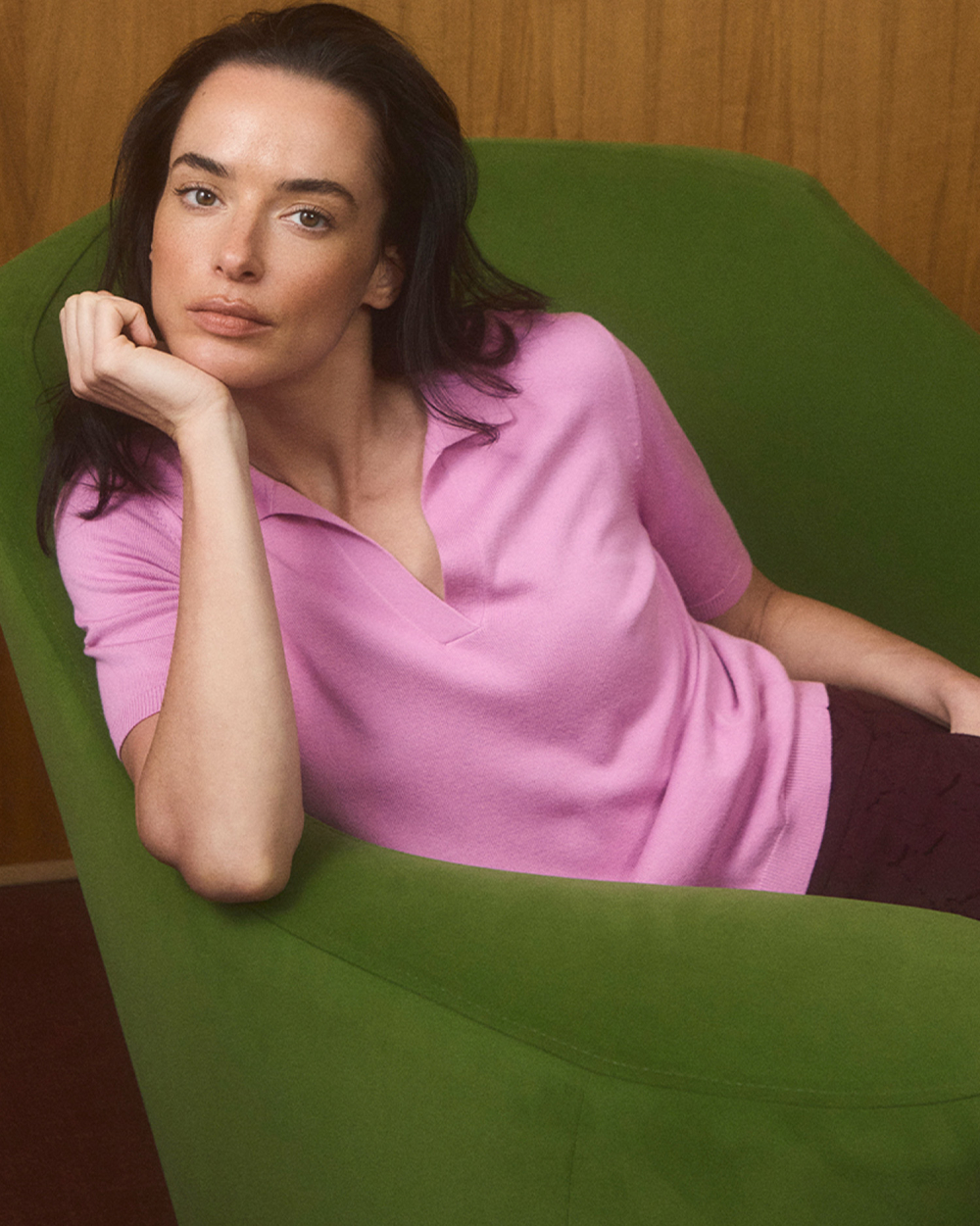 o femeie așezată într-un fotoliu, îmbrăcată într-un tricou polo