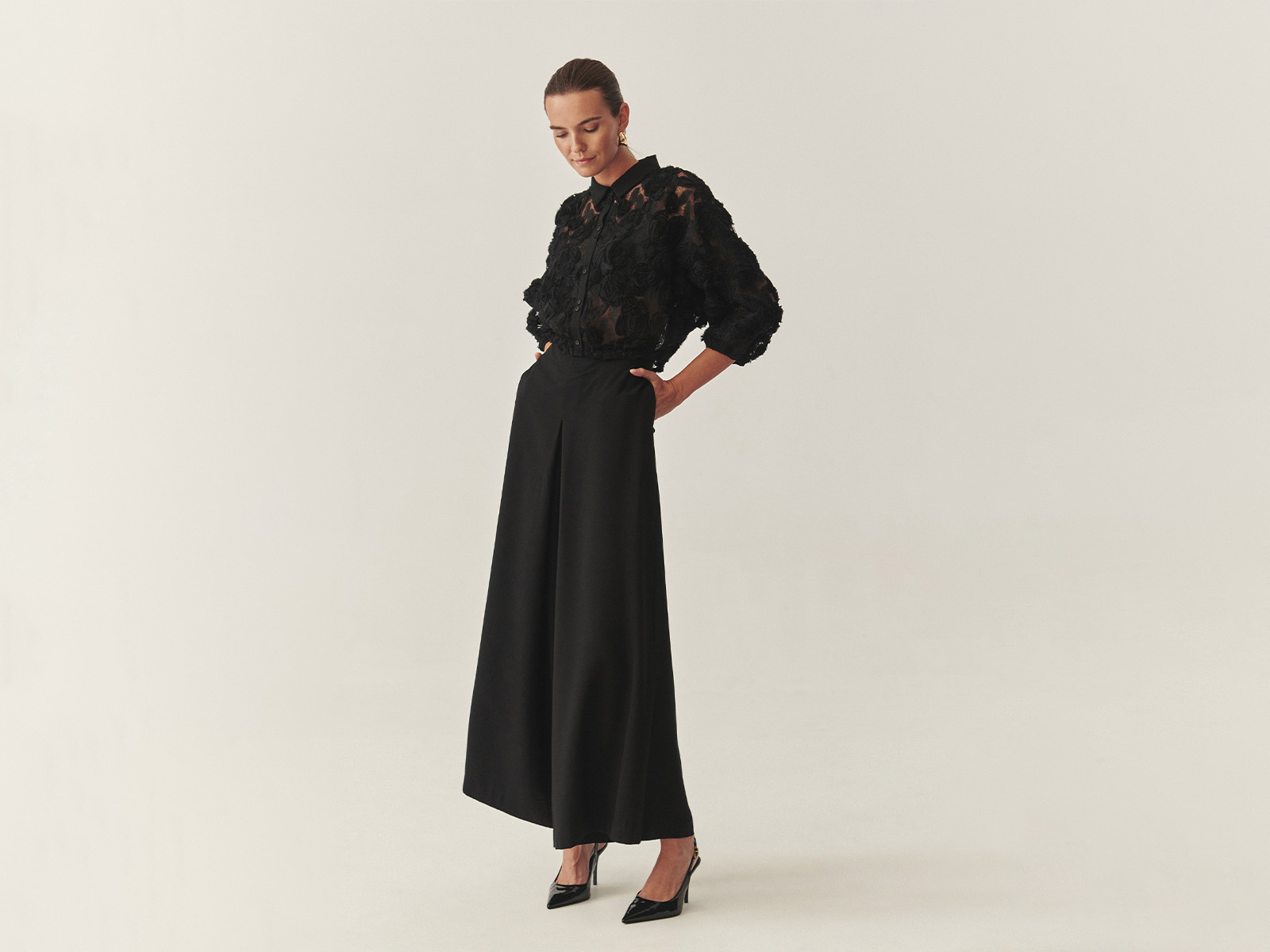 o femeie îmbrăcată într-o cămașă ornamentată și pantaloni lungi cu picioare largi