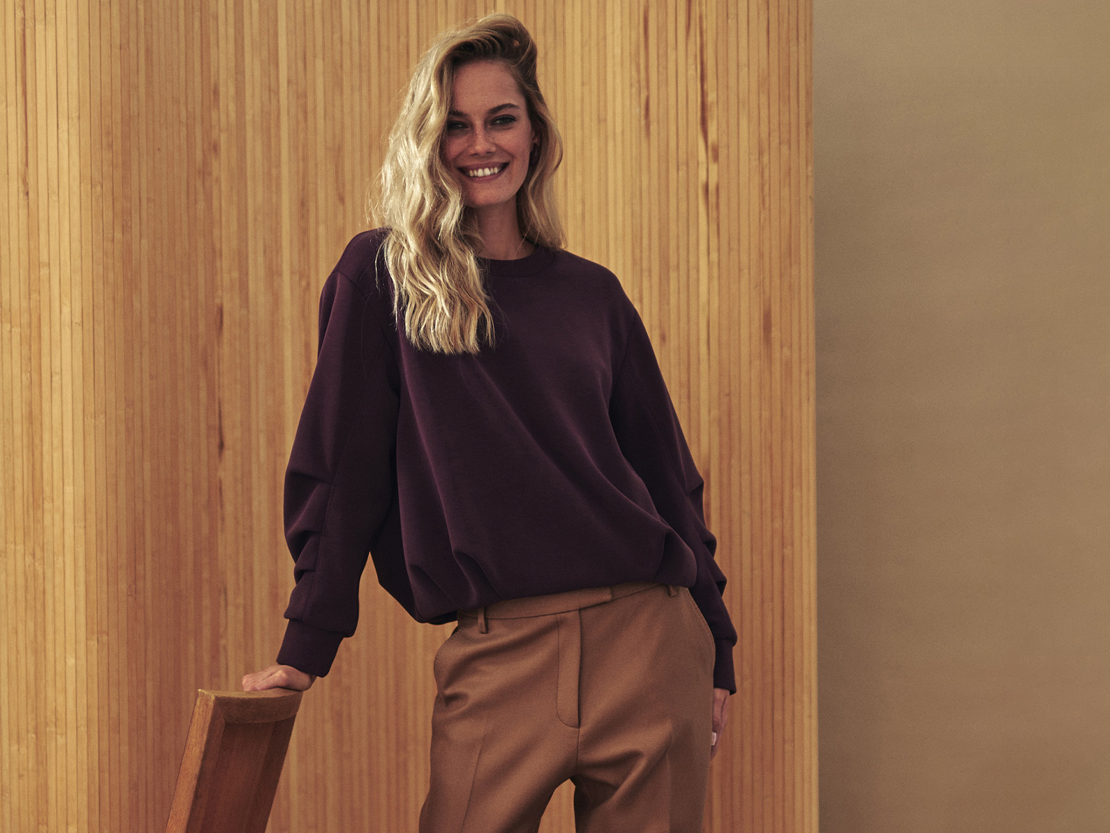 žena v bordovom svetri a béžových nohaviciach