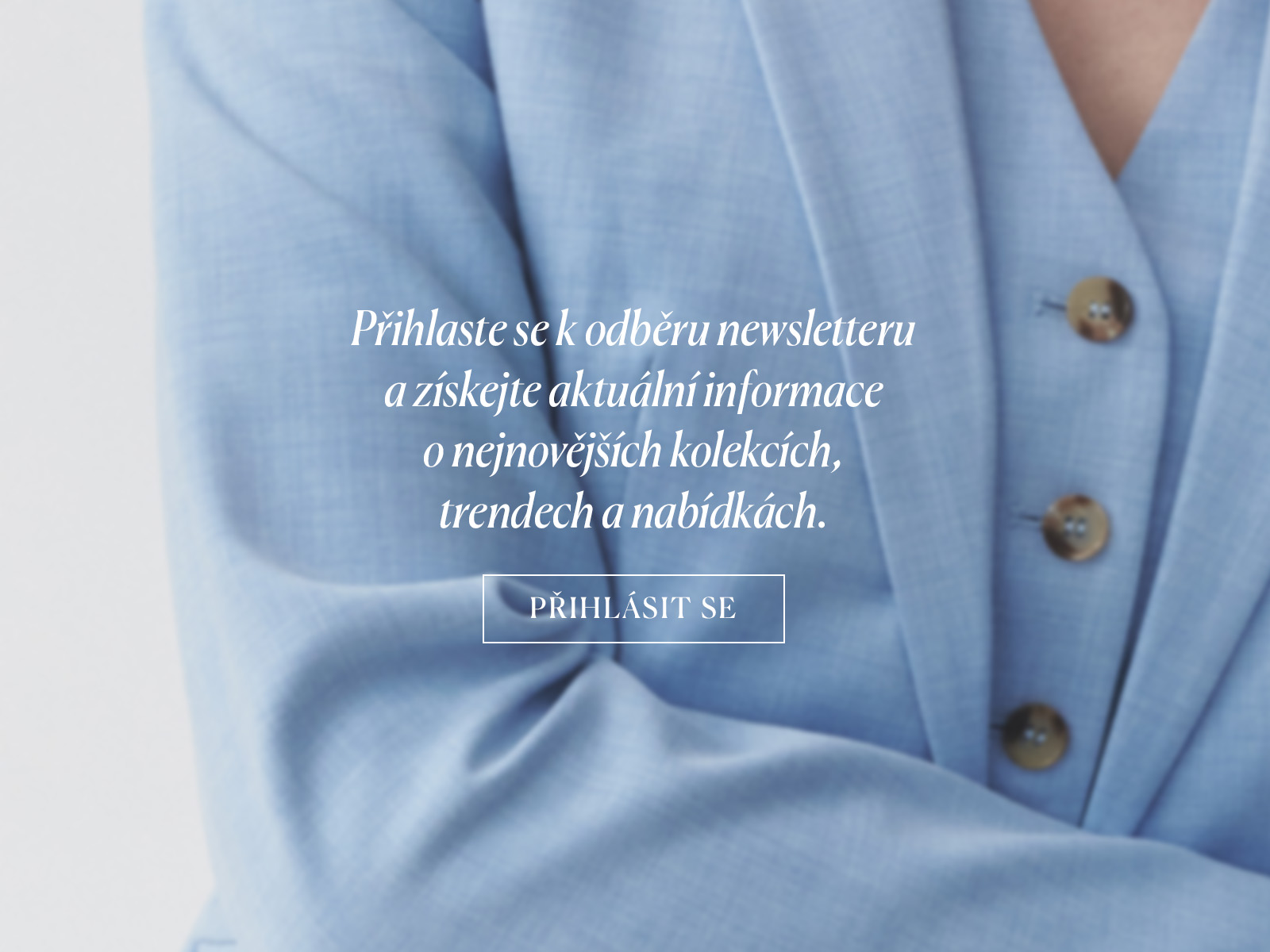 Detail rukávu světle modrého saka s textem propagujícím přihlášení k newsletteru na pozadí elegantní látky.