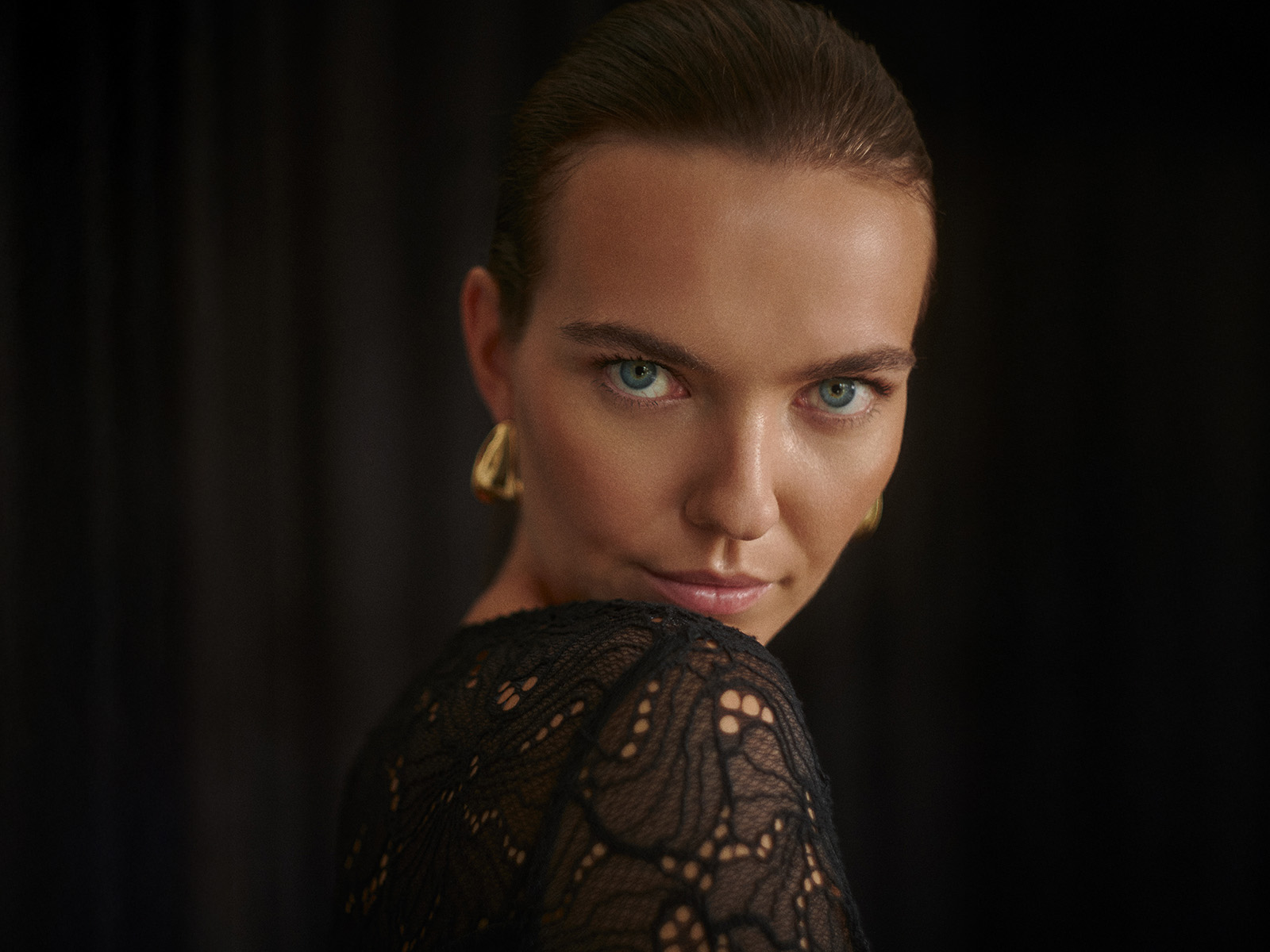 prim-plan al feței unei femei îmbrăcată într-o bluză din dantelă și cercei din aur