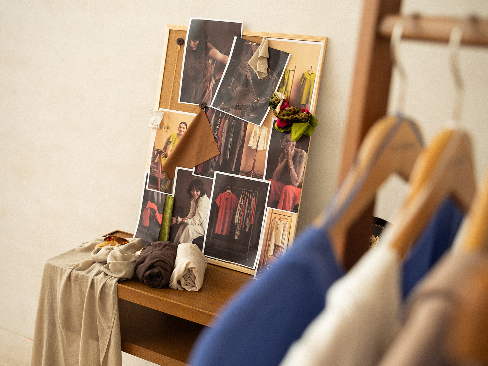 Panou de inspirație cu fotografii și mostre de țesături, așezat pe o masă din lemn cu materiale textile.