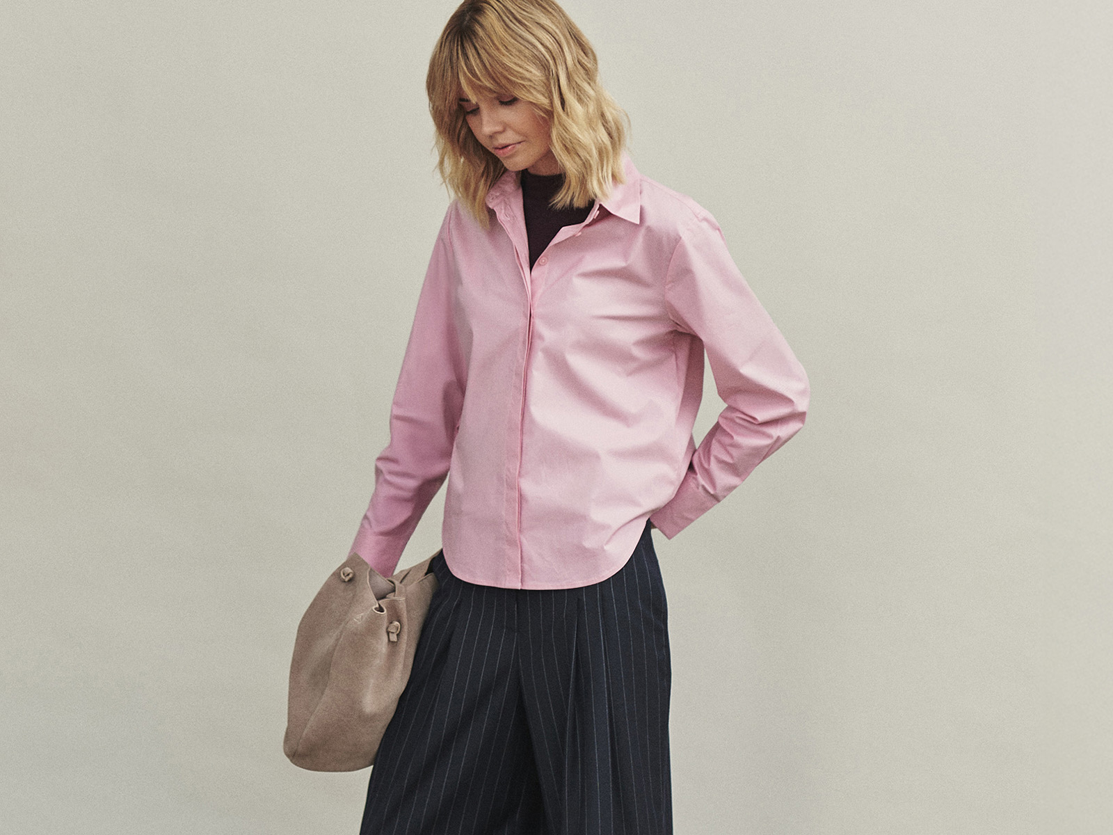 kobieta z torbą, w koszuli i spodniach o szerokim kroju 