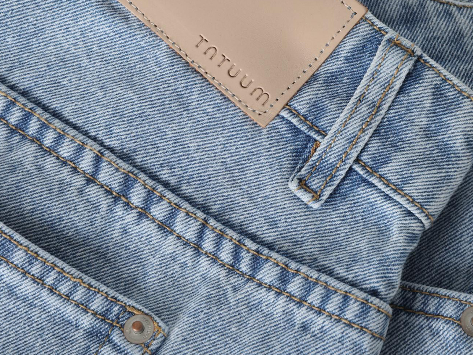 Detaliu al unei fuste midi din denim albastru deschis.