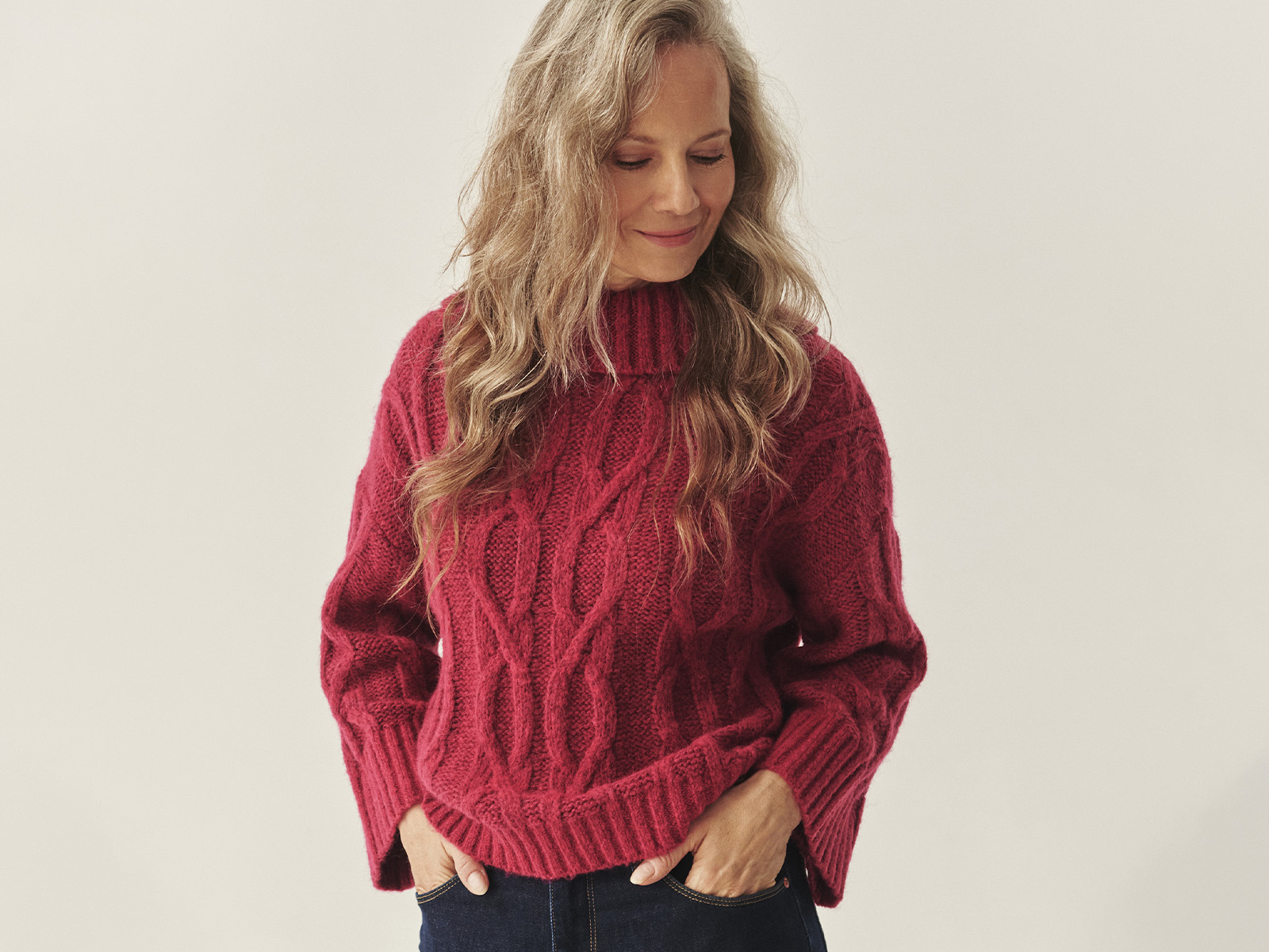 femeie zâmbitoare într-un pulover, privind în jos 