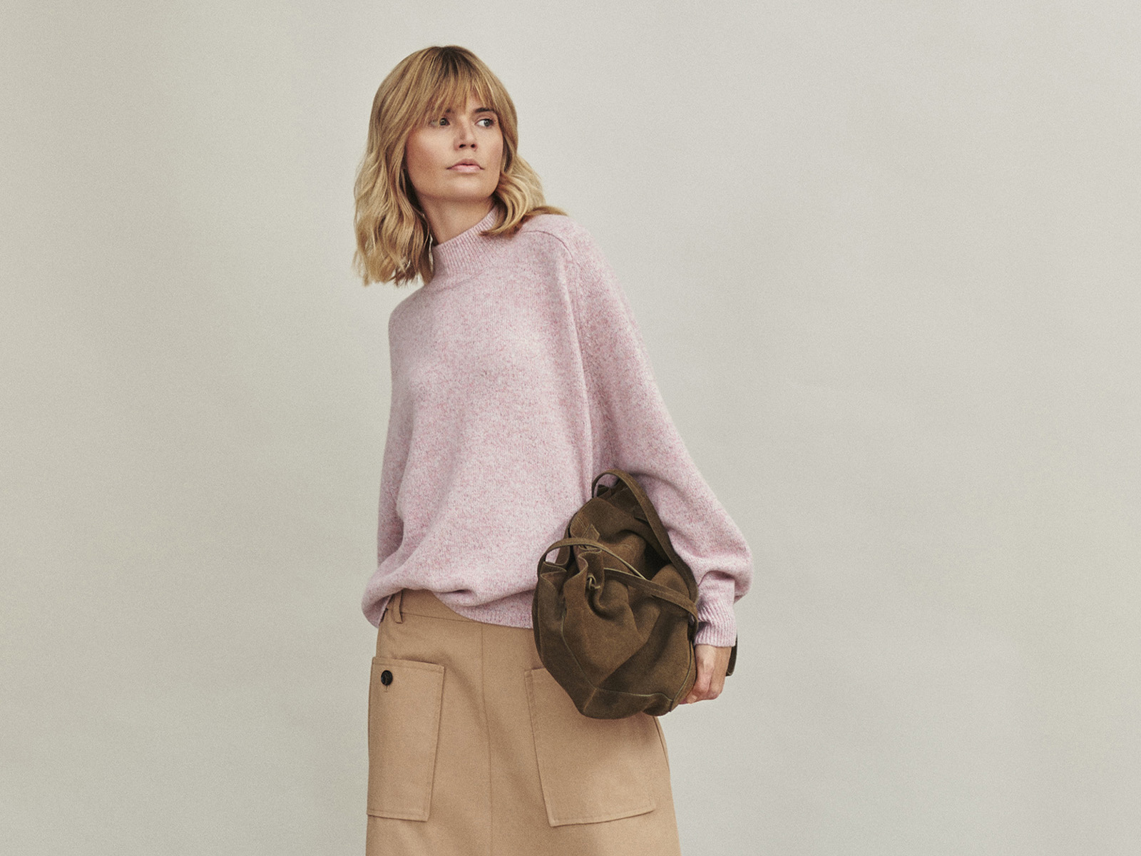 žena v béžové sukni a růžovém svetru