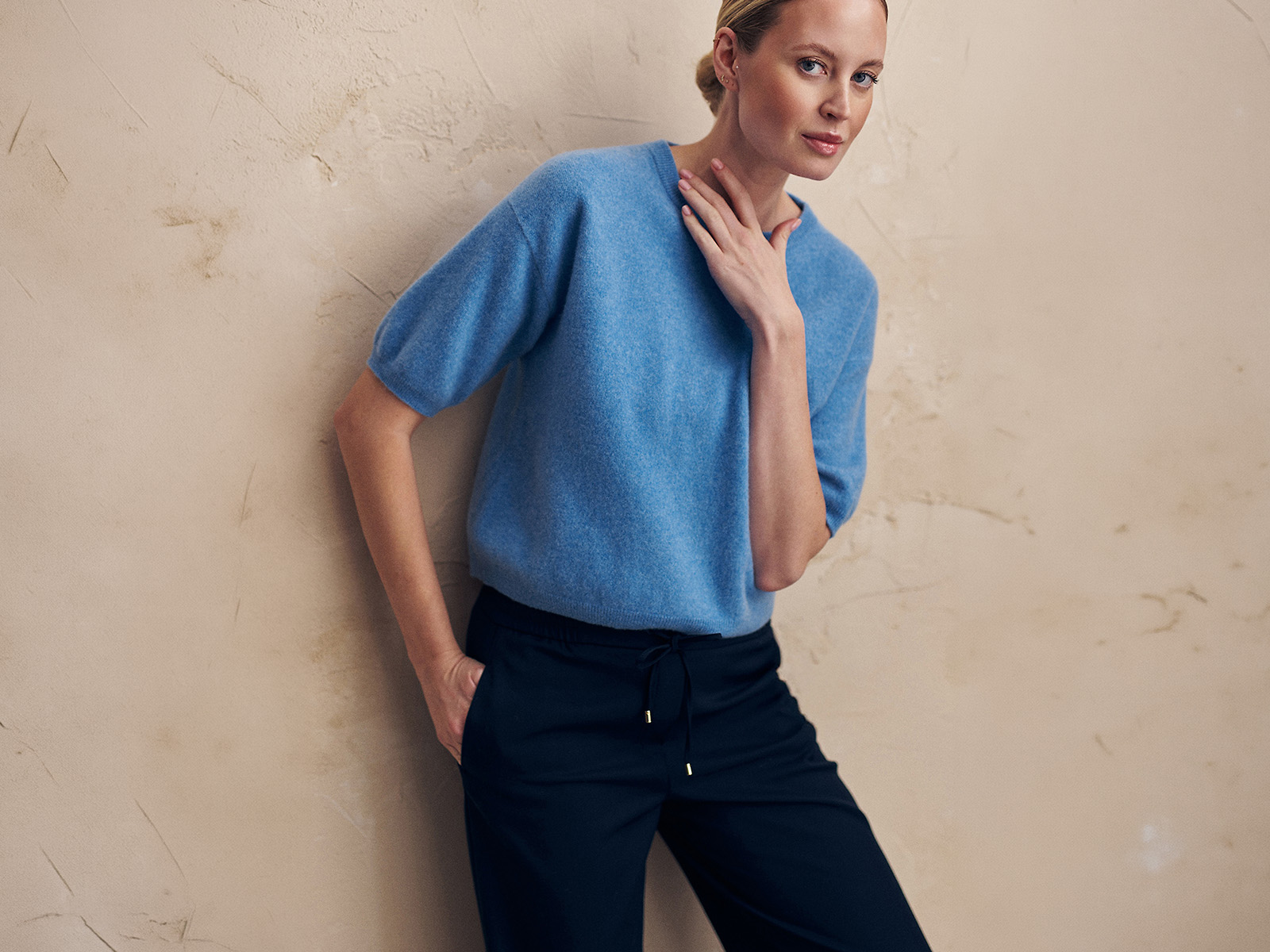 Kobieta w niebieskim swetrze i granatowych spodniach