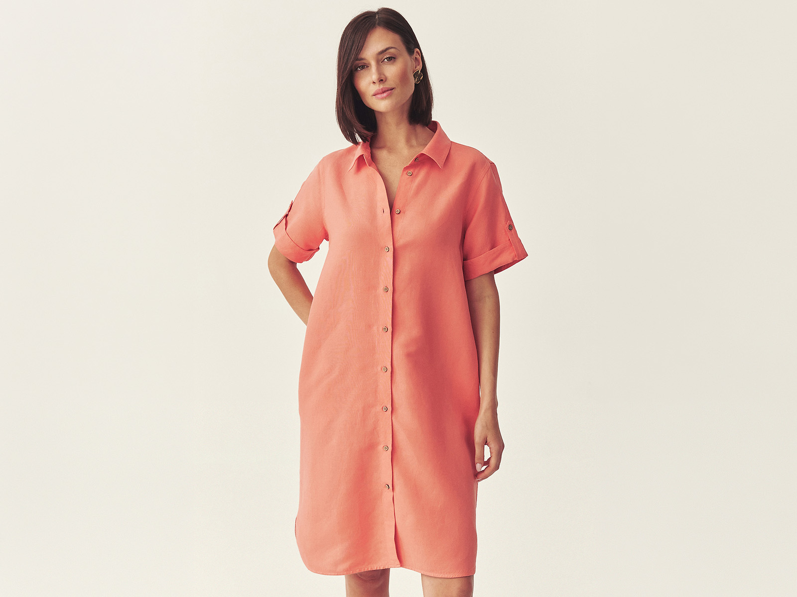 žena v korálové oversize košilové šatech